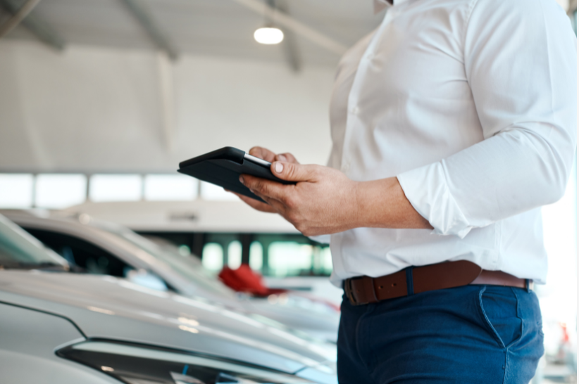 A picture of a man on his IPad in front of cars